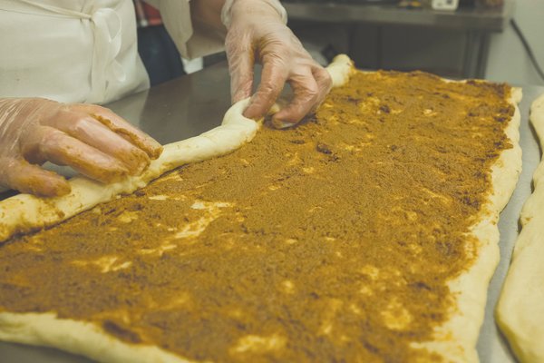 After spreading the cinnamon sugar filling, Chef Jule Roach rolls the dough.