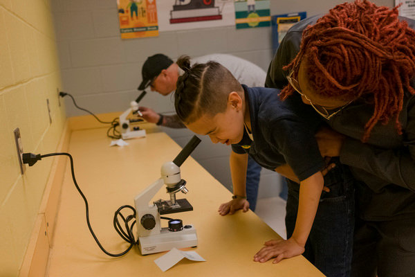 Danielle Johnanson holds her son, Tyler, up to a microscope at Foley Elementary's first STEAM night on Thursday.
