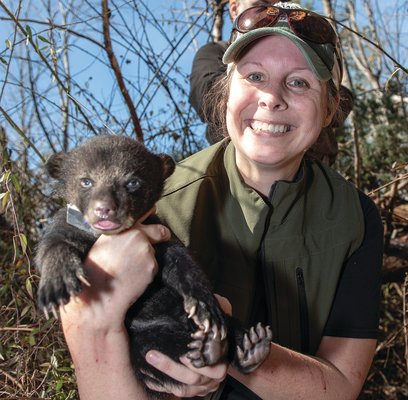 Traci Wood, State Wildlife Grants Coordinator with the Alabama Department of Conservation and Natural Resources' Wildlife and Freshwater Fisheries Division, is all smiles as she prepares to return a black bear cub to its den in northeast Alabama.