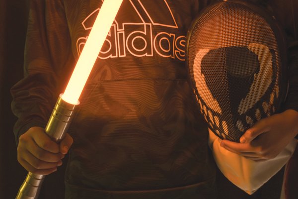 A student in Scott Prince’s Jedi swordplay class holds a lightsaber and helmet.