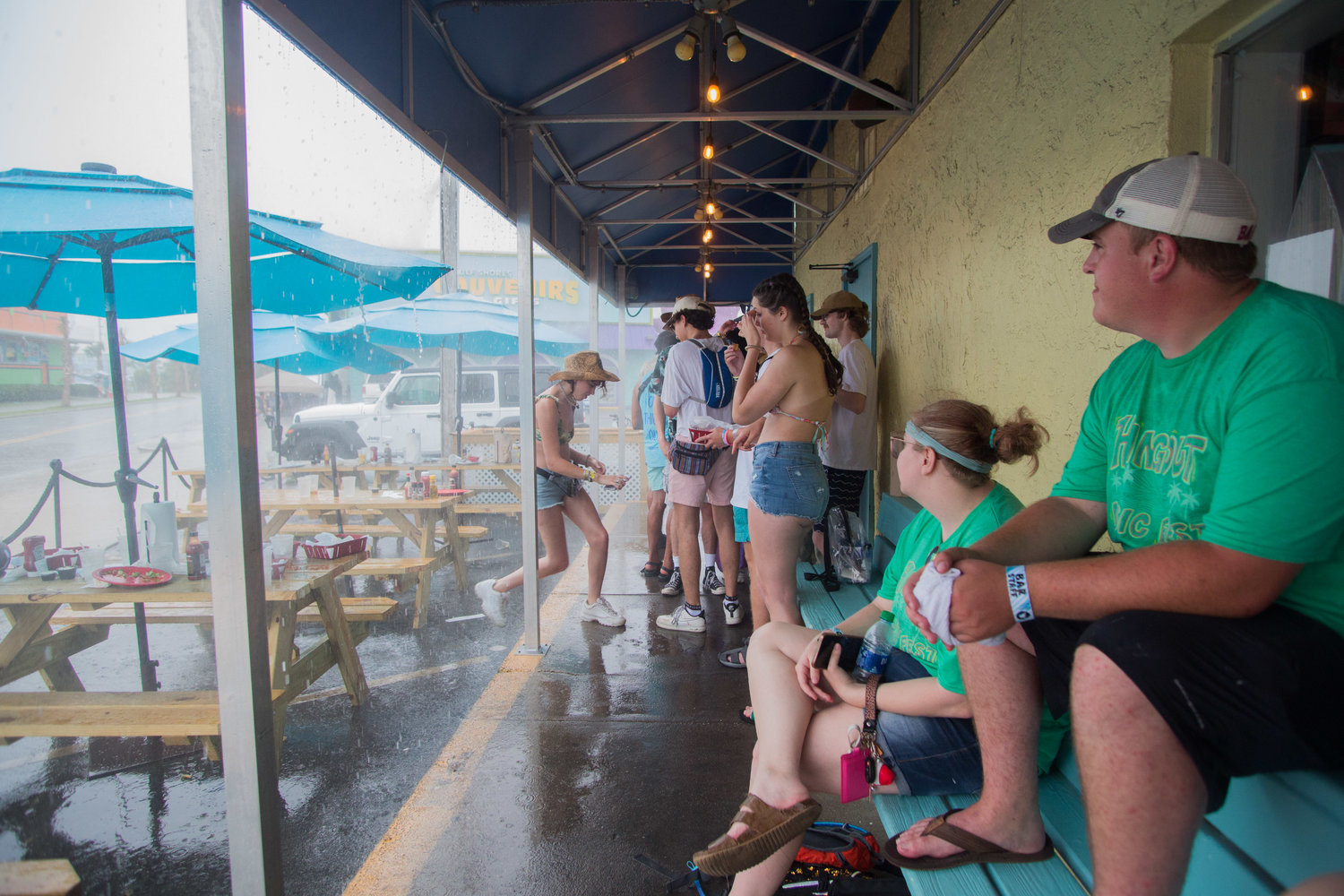 Festival goers take cover under the overhang at Shrimp Basket in Gulf Shores after being evacuated from the Hangout Music Festival site on Friday, May 20, due to lightning and severe weather.