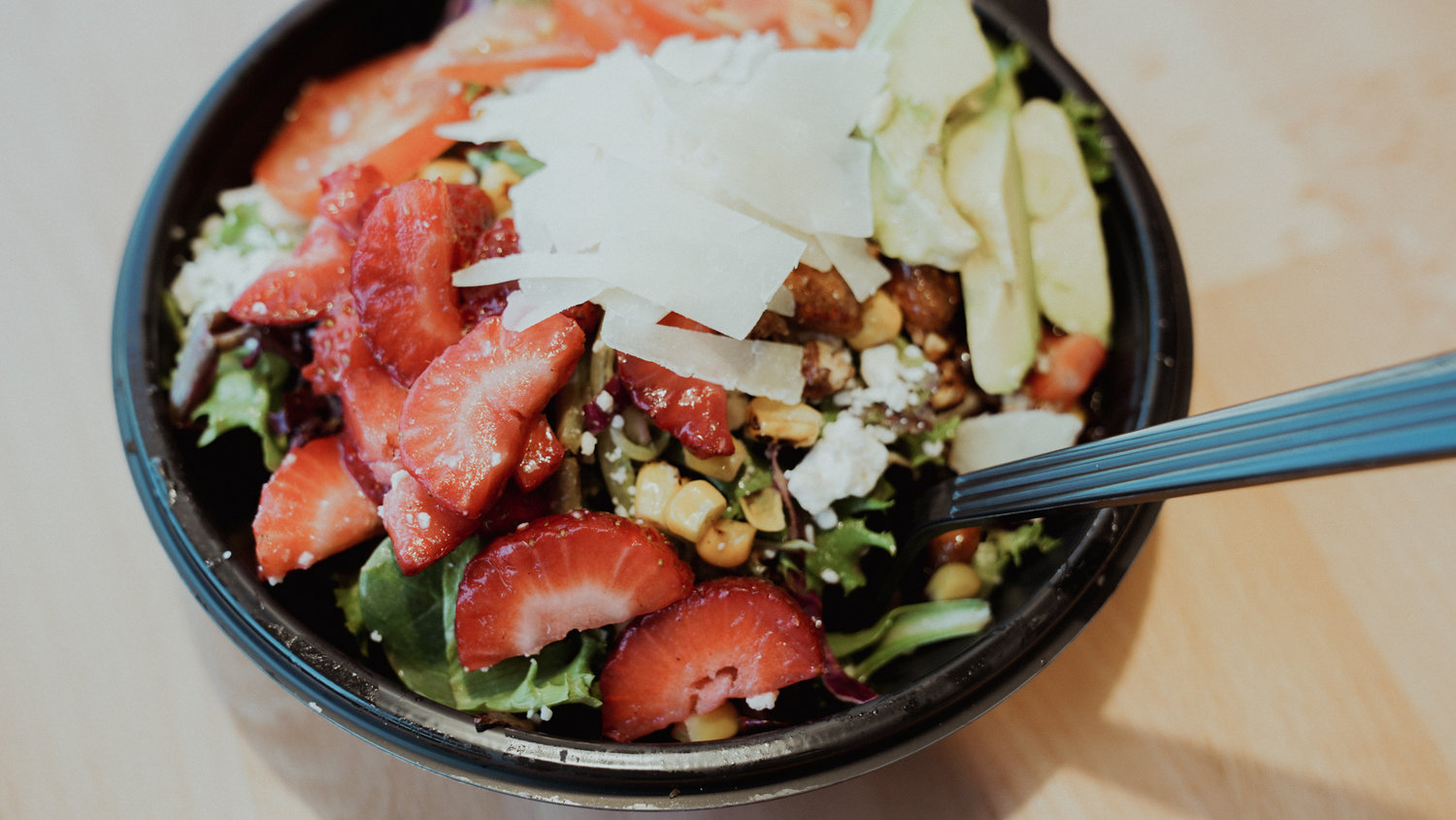 Valerio's Italian Farmer's Market Salad is is piled high with mixed greens, red cabbage, feta, avocado, strawberries, sweet corn, tomato, glazed pecans and a lemon basil dressing.
