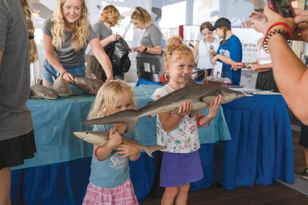 Two young girls have their picture taken shark specimens at the Gulf State Pier as a part of the park’s annual Shark Week.