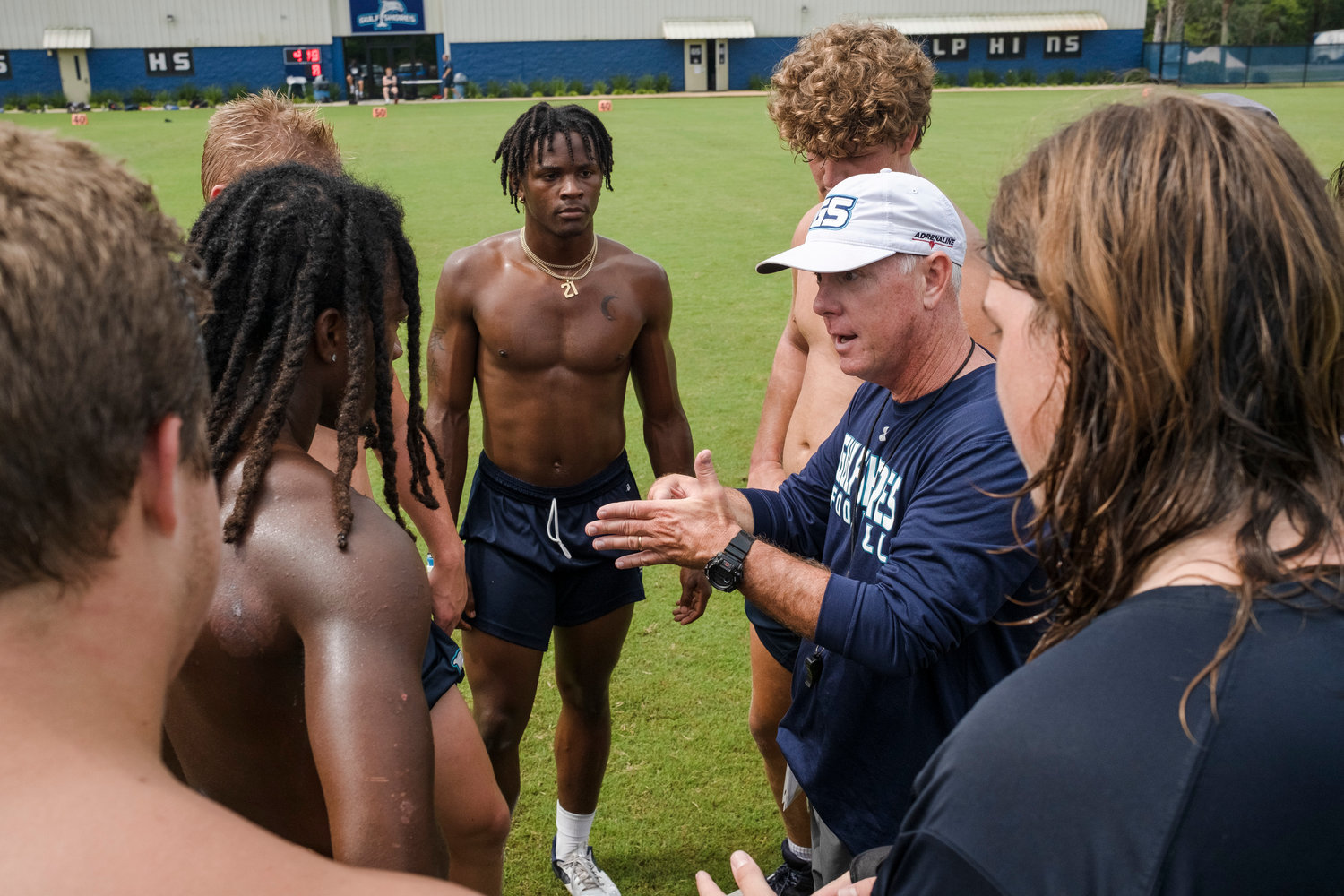 Gulf Shores offensive coordinator Kenny Edenfield meets with athletes during a drill at the Dolphins' July 20 practice at the high school.