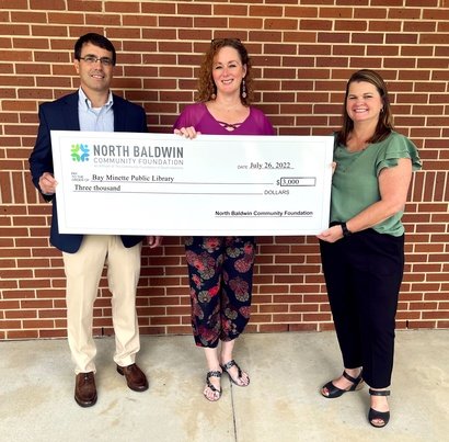Bay Minette Library Director Joanna Bailey, center, accepts the donation from North Baldwin Community Foundation representatives Scotty Lewis and Tina Covington. The library was one of nine organizations to receive a grant from the group this summer.