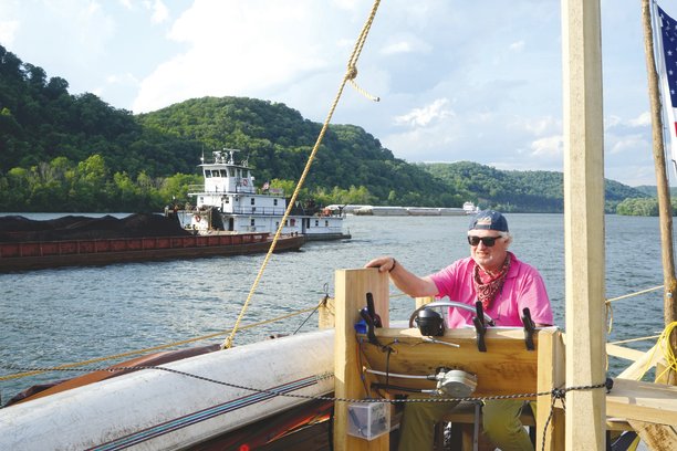 Buck Rinker navigates the Mississippi aboard "The Patience" alongside commercial barges.