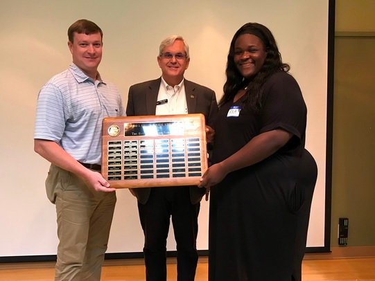 Scoggins Scholar Kyla Shaw holds a plaque listing the recipients of the Thomas S. Scoggins Memorial Scholarship. The plaque is permanently displayed at Fairhope High School. With her are Mark Martin, immediate past president of the Rotary Club of Fairhope (left), and Chad Clark, the club’s youth service chairman.