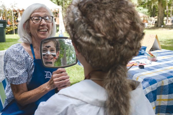 Warren Grider smiles while seeing his reflection after having his face painted by a member of the Daughters of the American Revolution at the Fort Mims massacre reenactment on Saturday in Stockton.