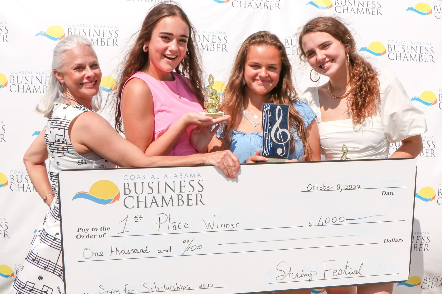 Chairperson Allison Pryor presents the $1,000 check to the 2022 Singing for Scholarships winner Maura Hawkins of Gulf Shores High School. She is joined by second place winner Victoria Holley of Spanish Fort High School and Luiza Salazar from Orange Beach High School.