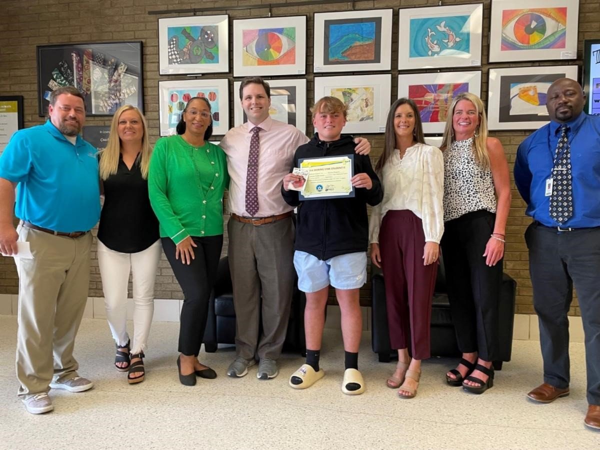 Daphne Middle School student Braxton Skoglund (center, holding certificate) is pictured with family members Chris and Sharon Skoglund, teacher Jamie Franklin, FOX 10 TV's Michael White, Baldwin EMC representative Kim Frank, family member Stephanie Cochran and Principal Kerry Edwards.