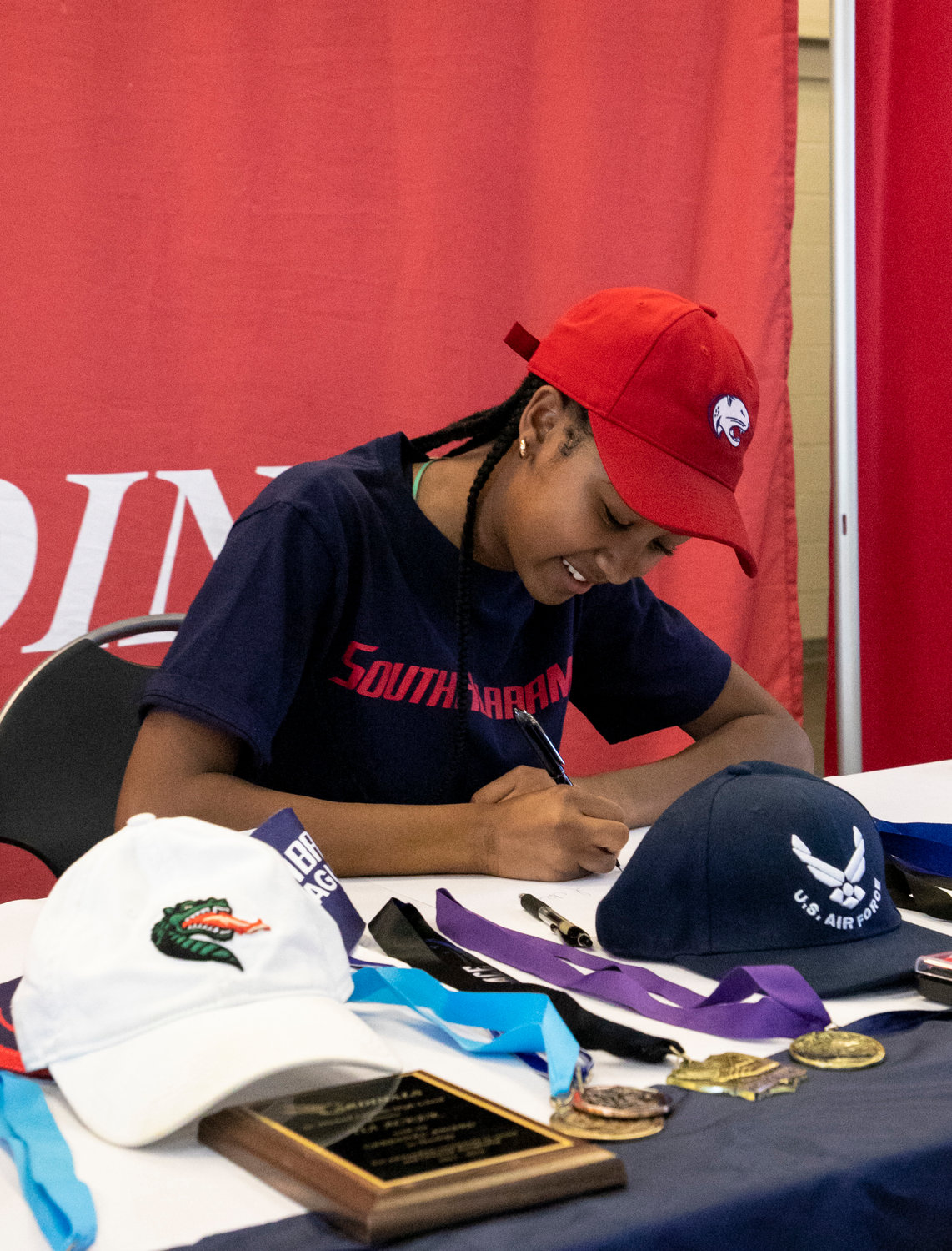 Tia Acker puts pen to paper to cement her commitment to the South Alabama Jaguar track and field program during a signing ceremony Wednesday, Nov. 9, at St. Michael Catholic High School. She chose South Alabama over UAB, Air Force and others.