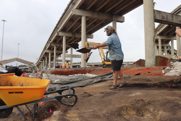 An archeologist slings dirt one shovelful at a time as crews work to uncover artifacts near the projected construction of the new I-10 bridge.