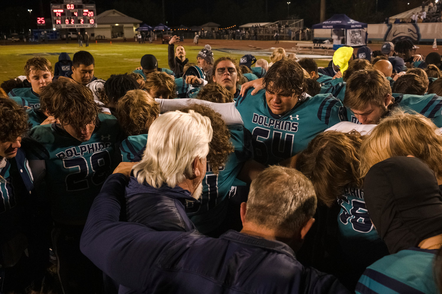 The Gulf Shores Dolphins meet one last time on the field of Mickey Miller Blackwell Stadium as character coach Fred Franks prays over the team following Friday night’s 20-14 loss to Faith Academy in the third round of the state playoffs.