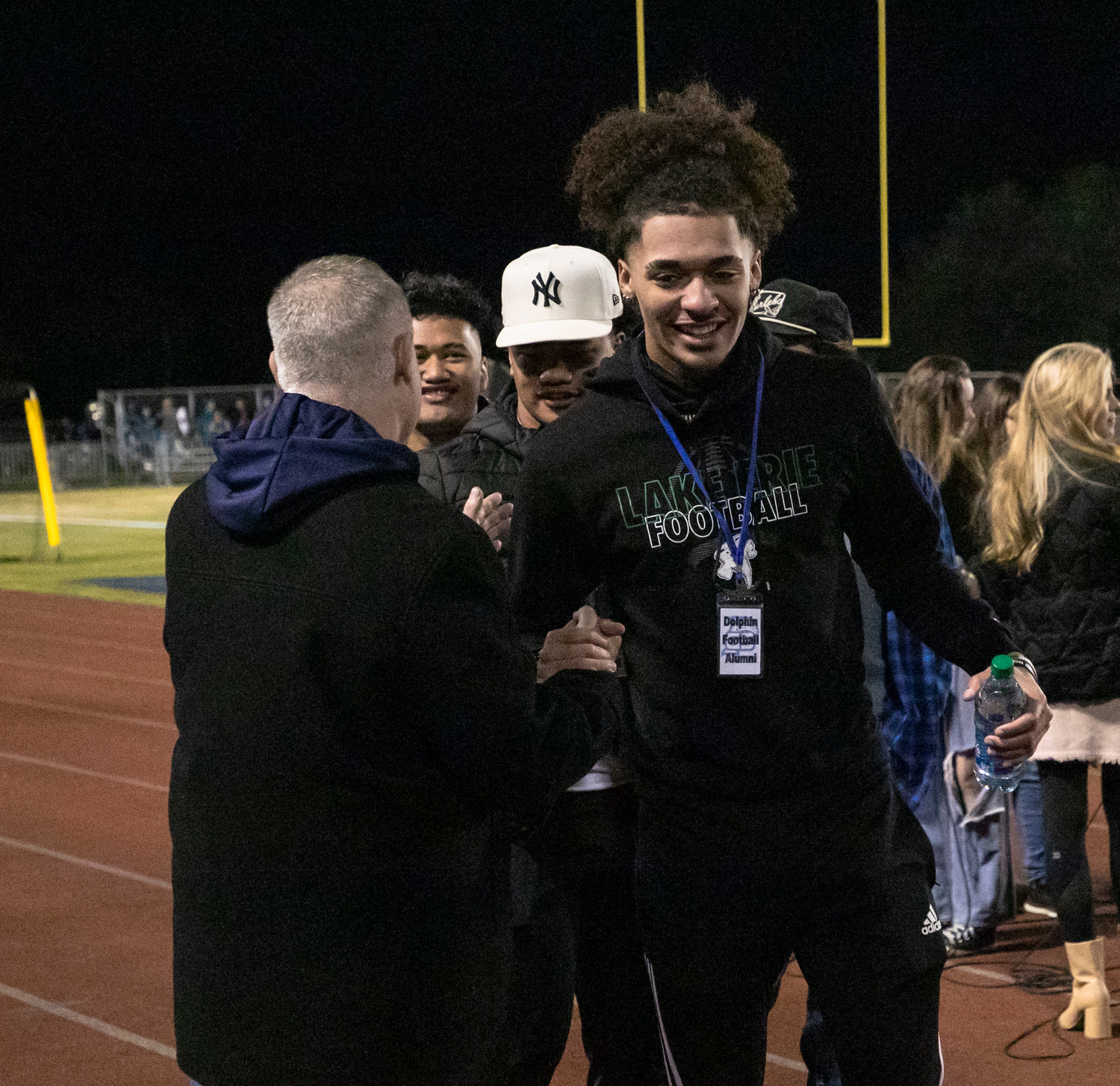 Taevon Anderson, a member of Gulf Shores High School’s Class of 2022, embraces Dolphin athletic director Kevin Tubbs after former players were recognized before Nov. 18’s state quarterfinal playoff game between the Gulf Shores Dolphins and Faith Academy Rams at the Sportsplex.