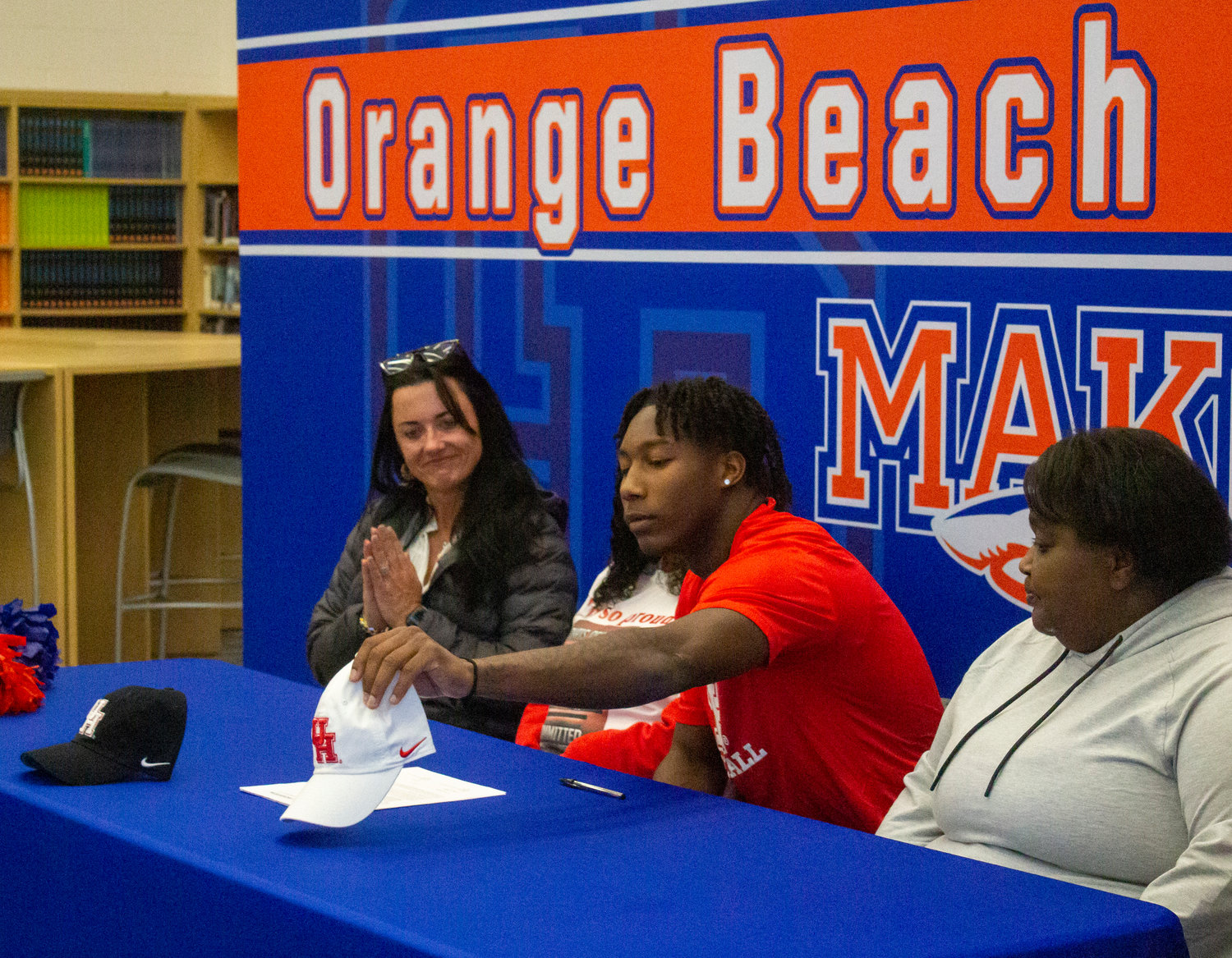 Chris Pearson picks up the University of Houston hat after he shared his appreciation to those in attendance of the National Signing Day ceremony Wednesday, Dec. 21, at Orange Beach High School.