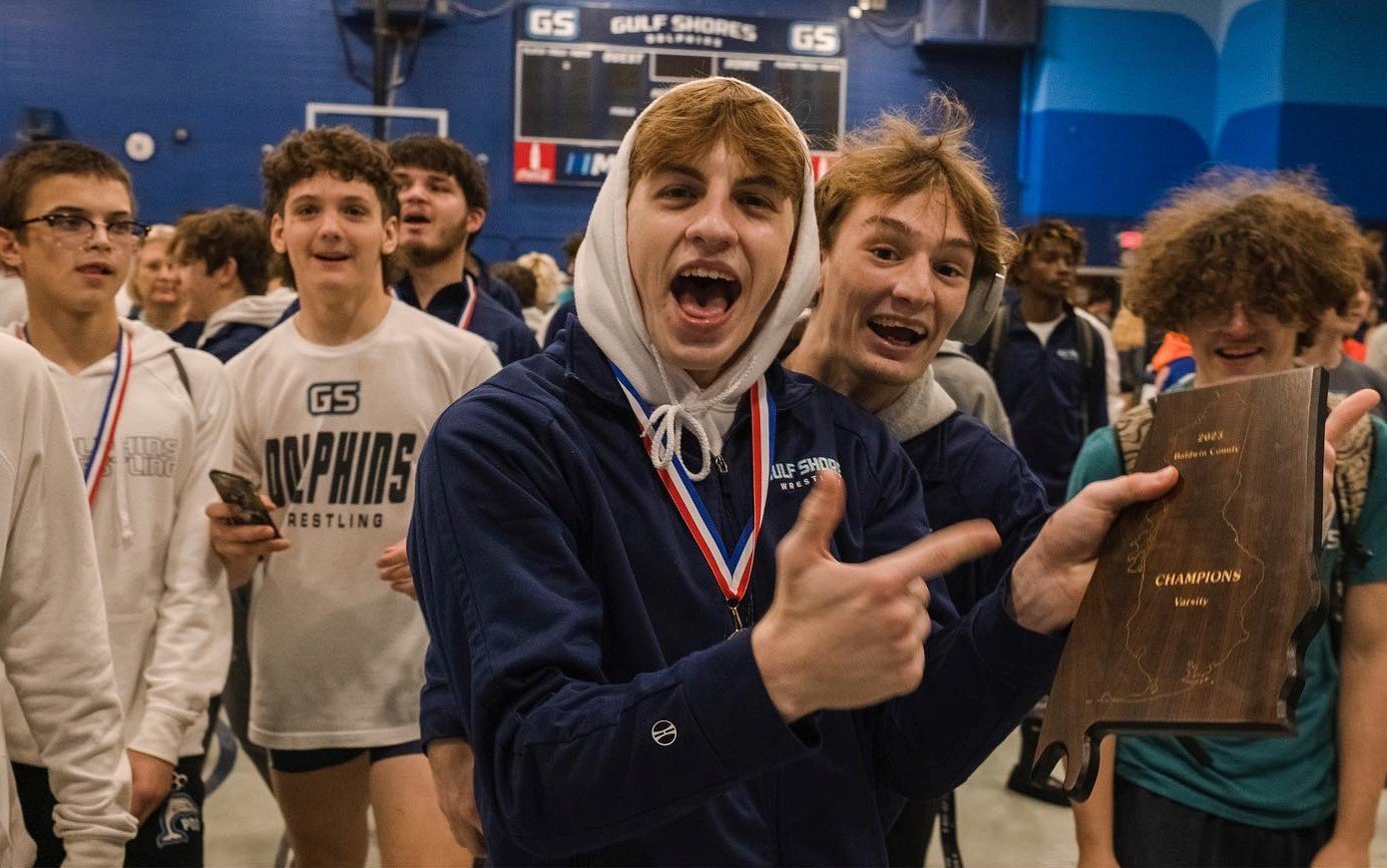 Gulf Shores senior Nick Carris, junior Ethan Sharkey and teammates celebrate with the Baldwin County wrestling championship plaque after he and six other Dolphins won their weight classes Saturday, Jan. 7. It marked a second straight county championship for Gulf Shores wrestlers.