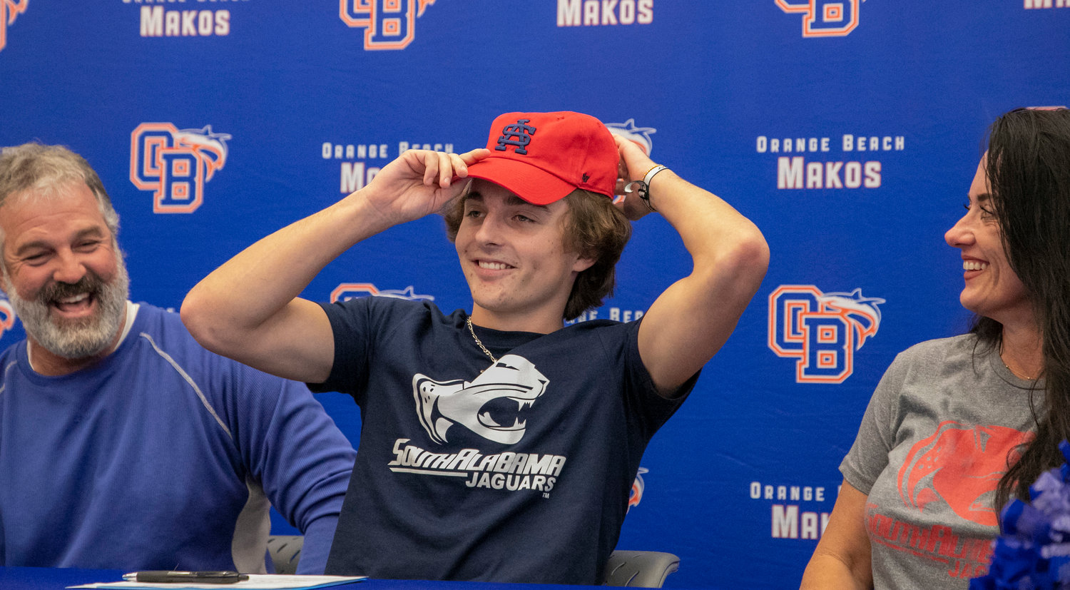 Cash Turner dons his new colors by putting on his South Alabama cap after he signed with the Jaguars as part of National Signing Day Wednesday, Feb. 1, at Orange Beach High School. The Mako quarterback joined teammate Chris Pearson in being the first from Orange Beach to sign with college football teams.