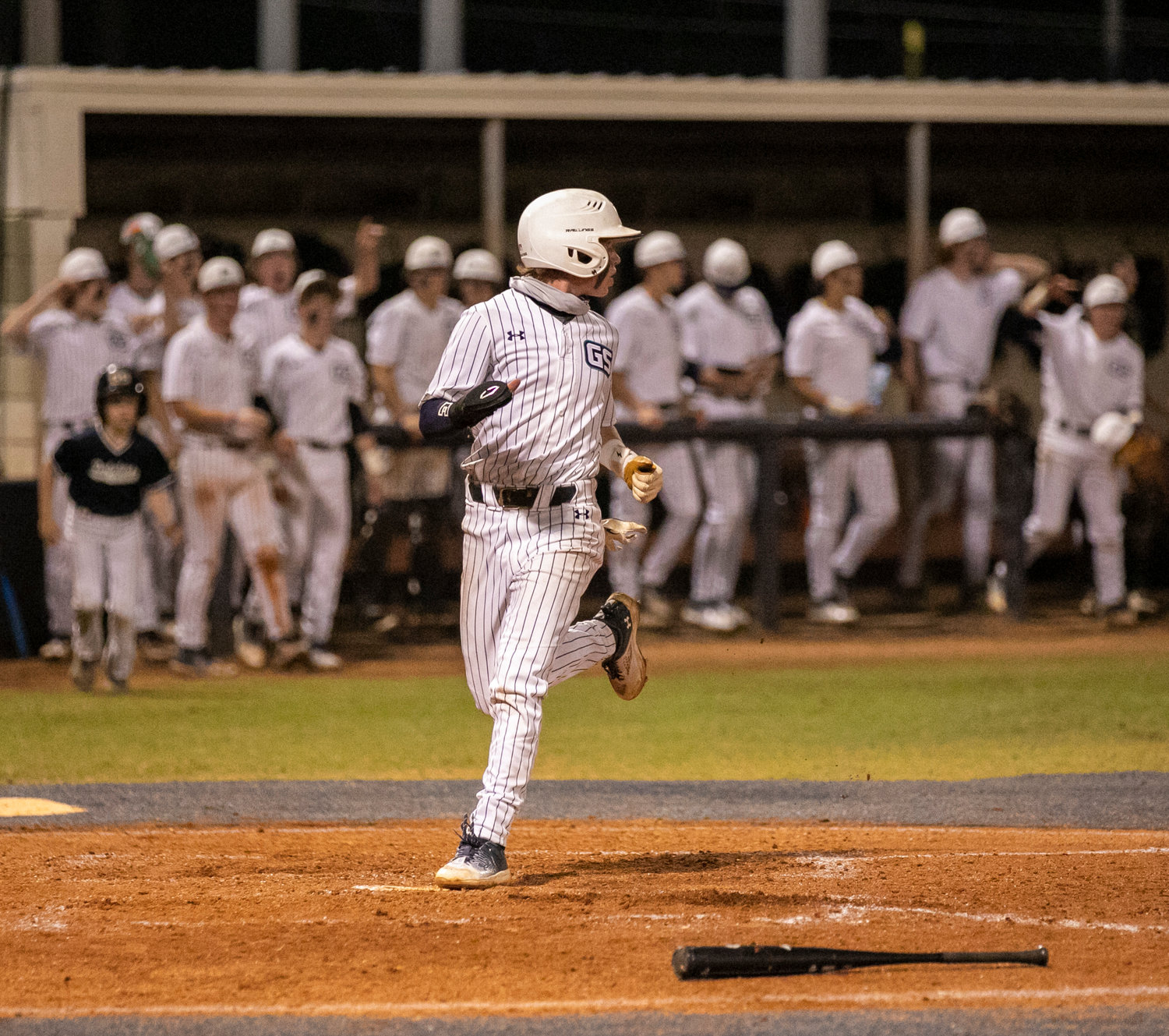 Gulf Shores’ Joseph Stephens comes around to hit home which scored the first run in the island rivalry between the Dolphins and Orange Beach Makos Friday night, Feb. 24, in the teams’ first meeting.