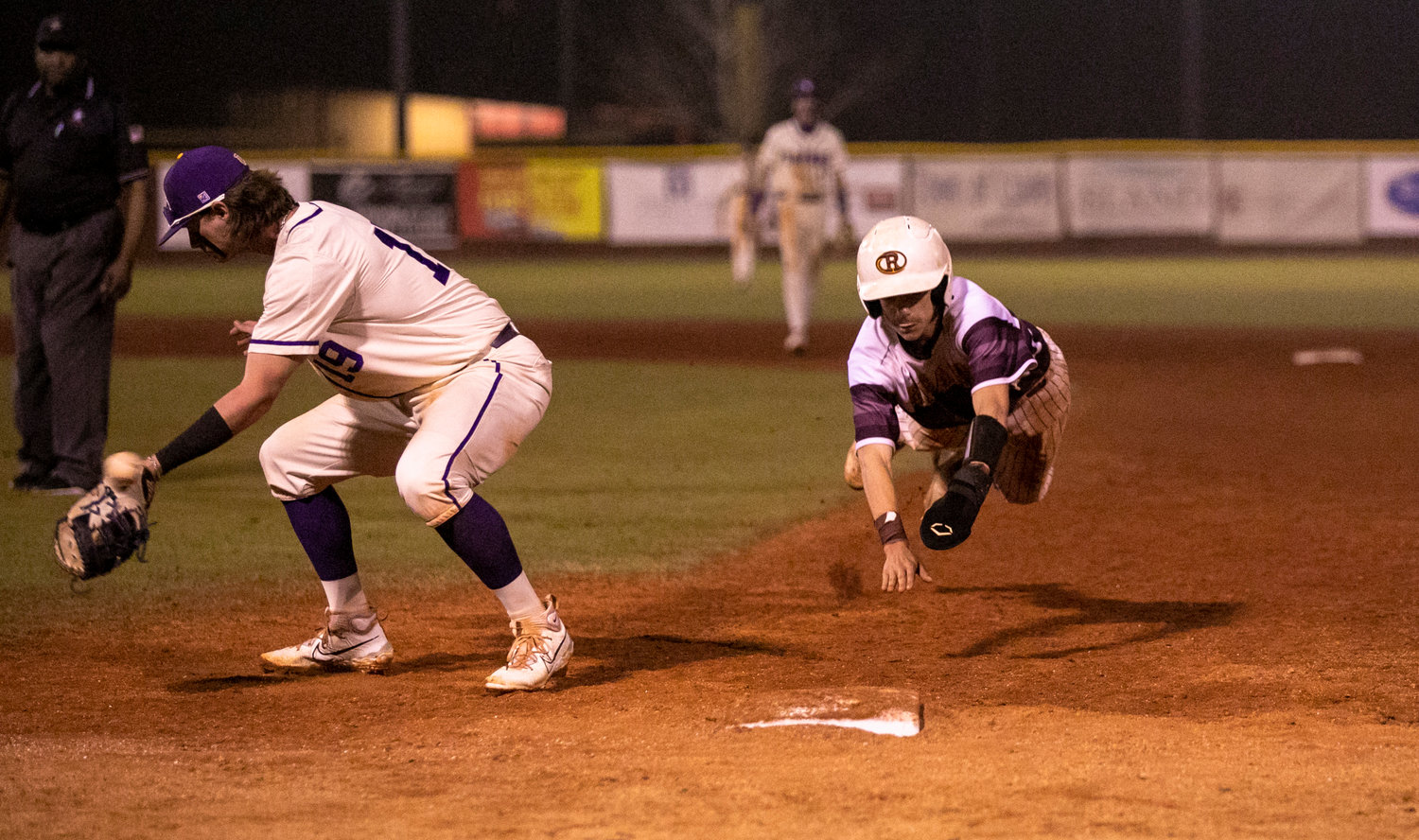 Robertsdale junior Chris Weeks dives back into first on a pickoff attempt Saturday in South Alabama Showdown action against the Daphne Trojans at home.