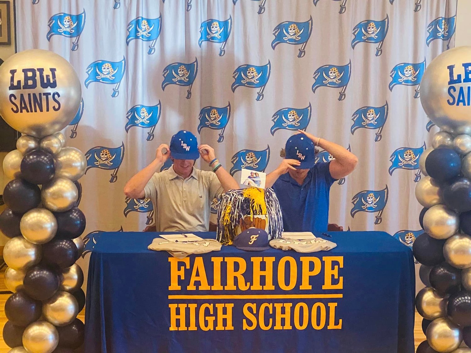 Fairhope seniors Hollon Brock and Jackson Hatcher don the cap of their college team after signing with the Lurleen B. Wallace Saints during a ceremony Sunday, March 5. The pair helped the Pirates claim the Class 7A Area 2 title last season with an 8-1 record in the group.