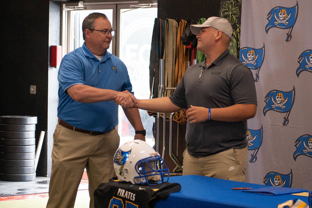 Mickey Herrick and Fairhope head football coach Tim Carter share an embrace during a Sunday signing ceremony where the Pirates’ center sealed his commitment to join the Warner Royals after his time at Fairhope. No Off Season training facility in Daphne hosted the ceremony.