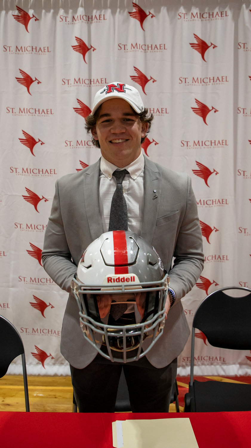 Justin Helper shows off his latest project of a helmet painted half St. Michael colors and half Nicholls State colors during the March 27 signing ceremony at the high school. He said it took him and his father Corey about four hours of painstaking effort to complete.