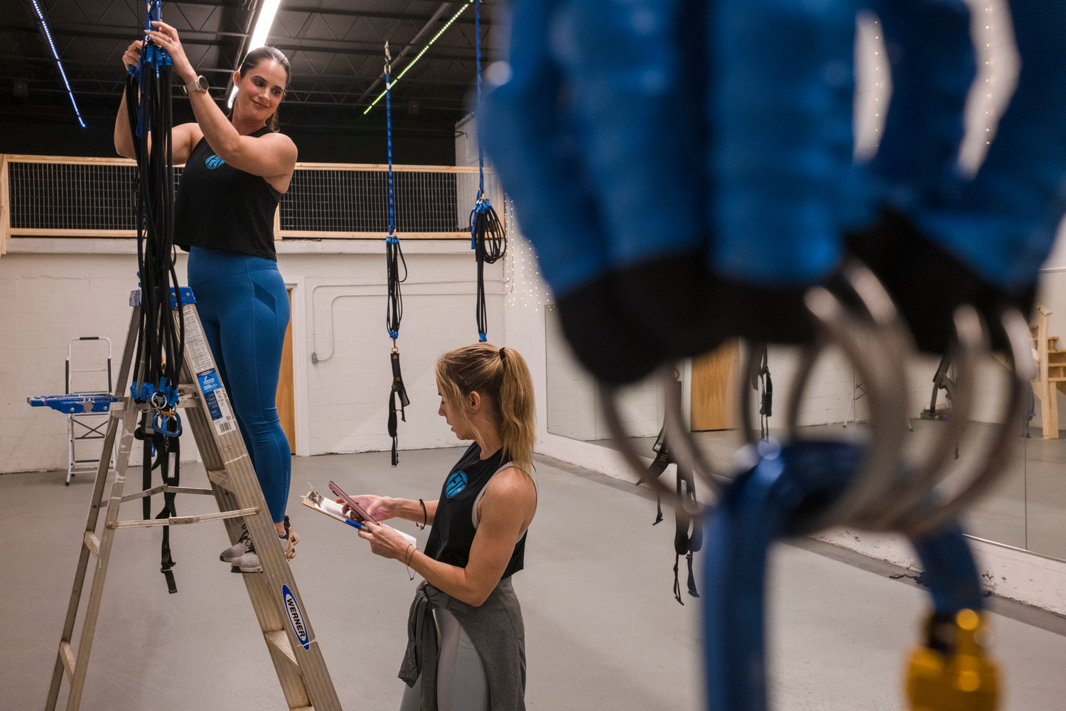 Lauren Babcock and Jessica Watkins prepare the equipment before a Sling Bungee workout.