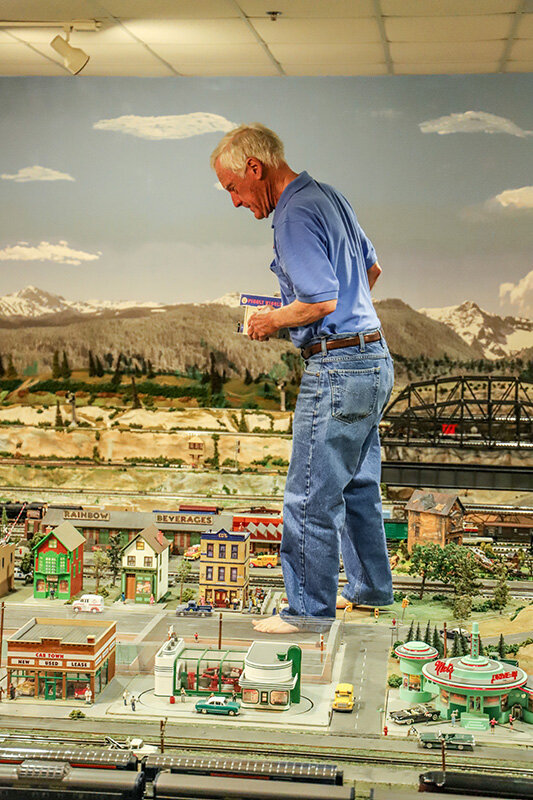 Bob Irwin walks carefully through the model train exhibit to make repairs