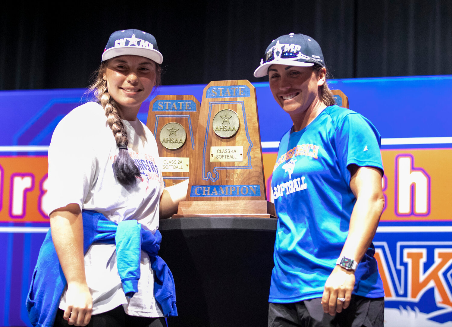 Orange Beach’s Kaitlynn Robertson and coach Katelyn Boyd take a picture with the newest of three state championships won by the Mako softball teams in the last three years. Sunday, May 21, the squad was recognized by the community with a welcoming ceremony.