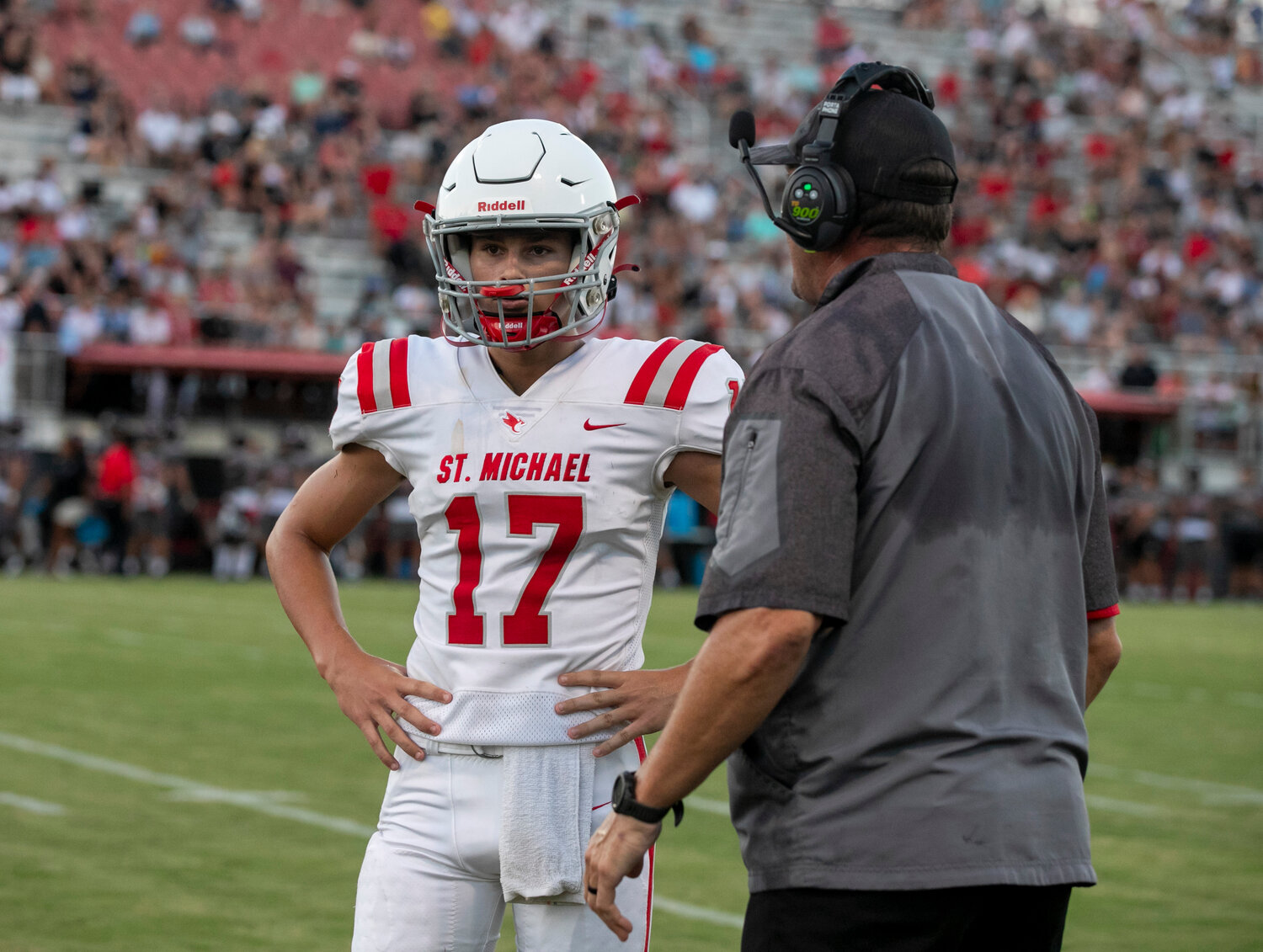 St. Michael Catholic quarterback Gunner Rivers meets with head coach Philip Rivers to get a play call Thursday, Aug. 17, in Spanish Fort during the Cardinals’ jamboree against the Toros. Gunner, a freshman, is set to take over the offense for his father who also wore number 17 over his 17-year NFL career.