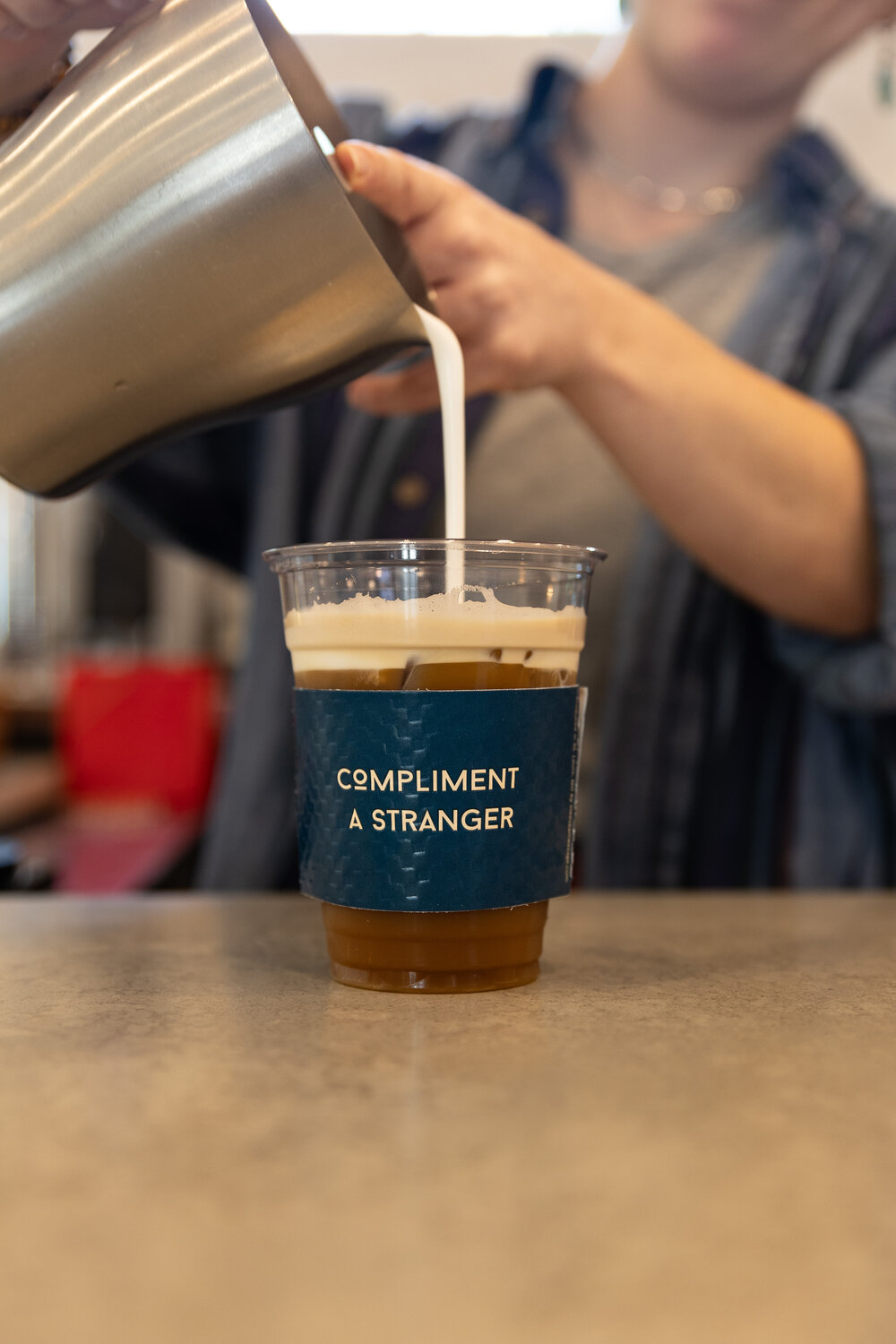 Kind Cafe features cup sleeve with a word of encouragement. Upon making an iced caramel apple coffee with cold foam, the cup was decorated with a sleeve that read "compliment a stranger."