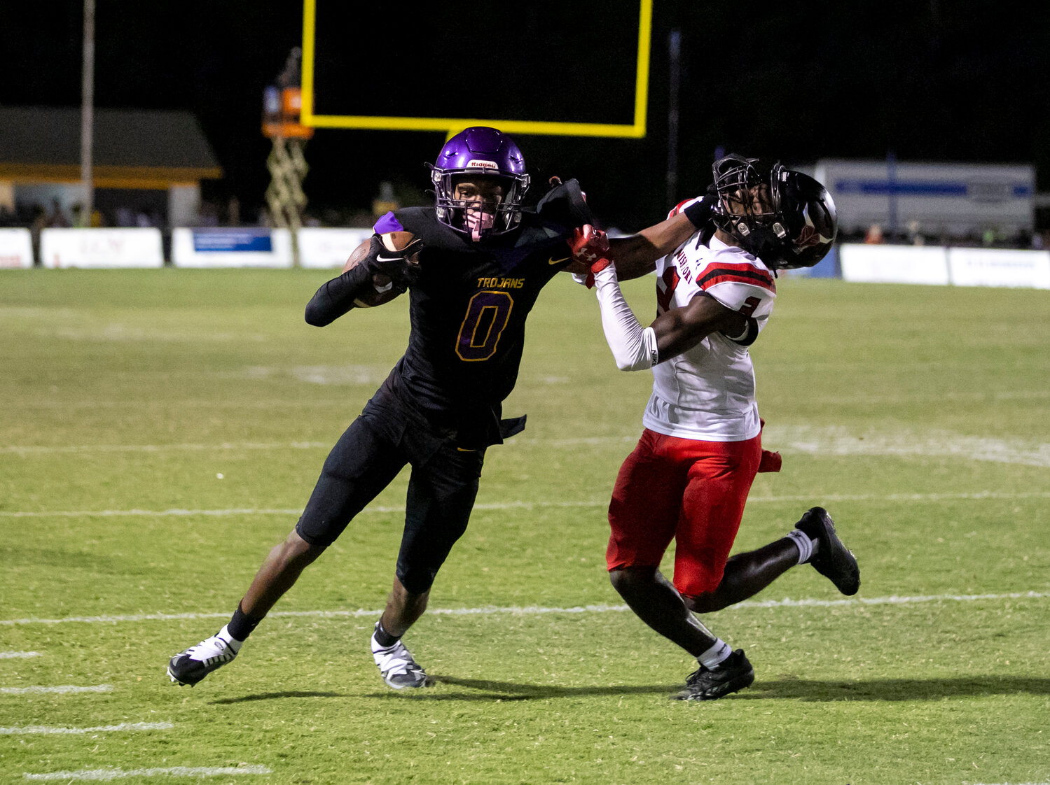 Daphne sophomore CJ Gardner (0) delivers a stiff arm at the end of his run after a catch in the first half of Friday’s rivalry game against the Spanish Fort Toros at Jubilee Stadium. The Trojans scored on all four of their first-half possessions in their first game using all-black alternate uniforms.