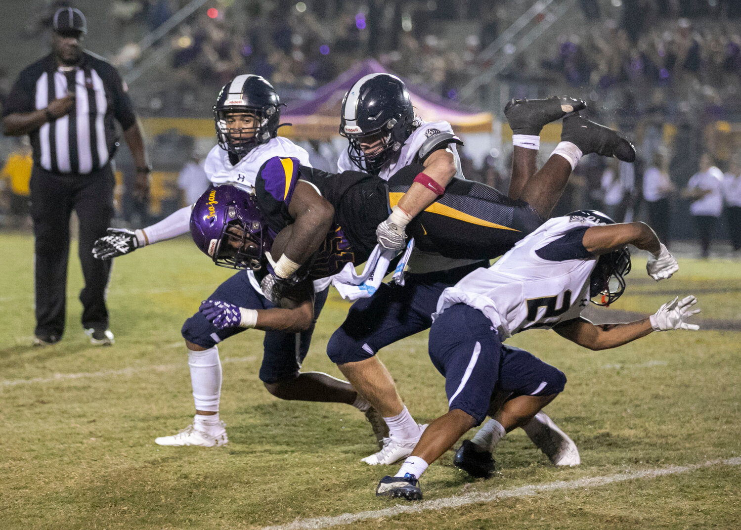 Foley senior Greg McGowan (21) is joined by junior Sam McClellan (43) and senior Andre Purdie (10) in upending Daphne senior Nick Clark (45) on a run during the second half of the Class 7A Region 1 game between the Lions and Trojans at Jubilee Stadium on Friday, Oct. 27.