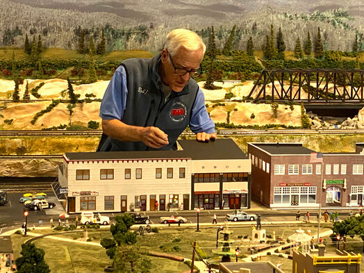 Bob Irwin works on the replica of the Holmes Hospital building, which is the latest addition to the model railroad display at the Foley Depot Museum. The model shows the building as it appeared in the 1940s.