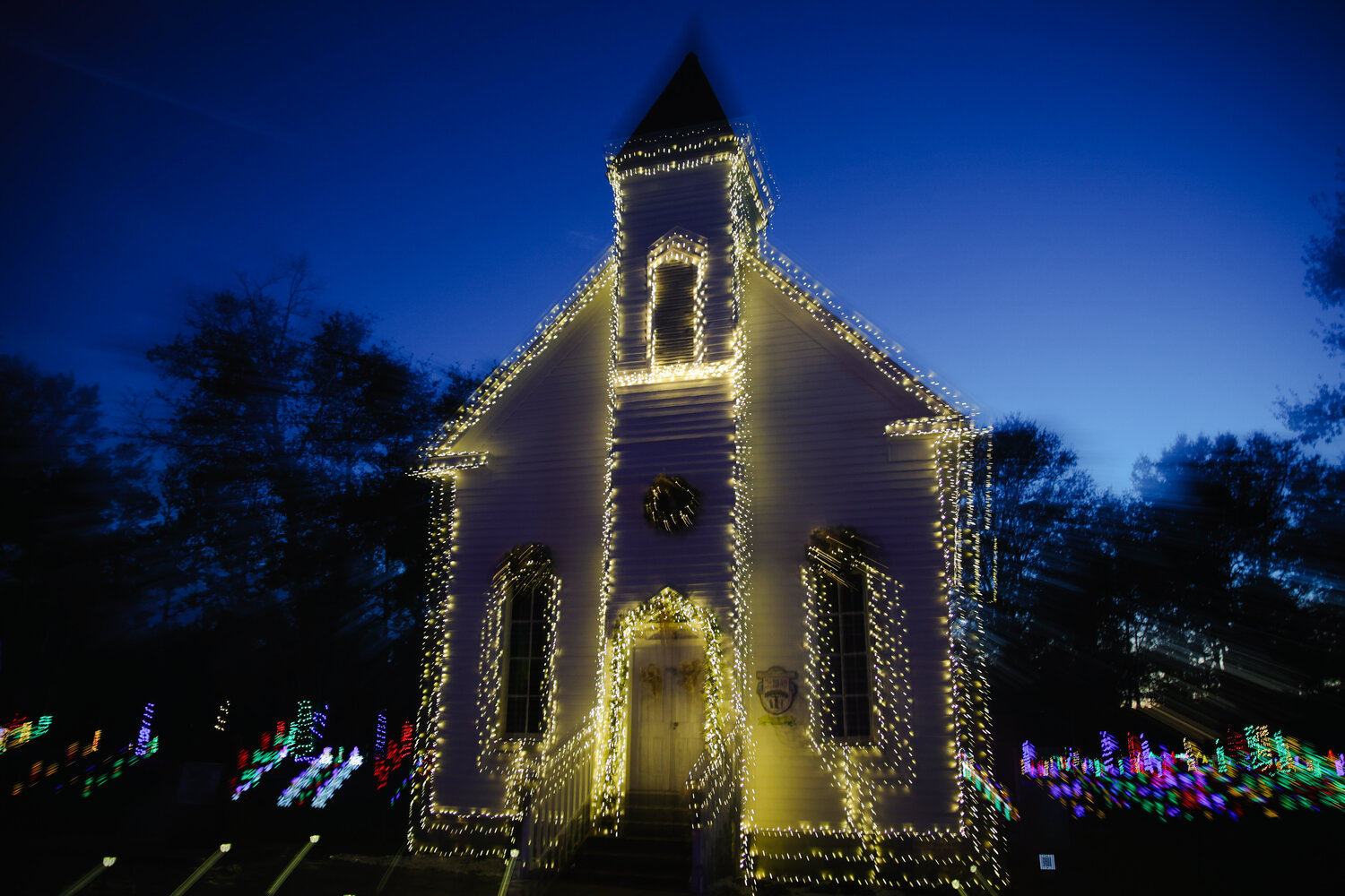 A chapel located at Bicentennial Park features lights wrapped all around it to illuminate the building, making it stand out among the colored Christmas tree lights.