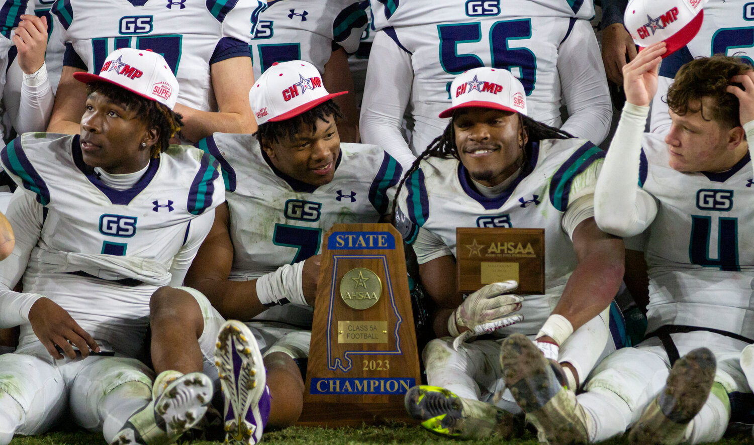 The Gulf Shores Dolphins, including Braden Jackson (1), Jamichael Garrett (7), Ronnie Royal (2) and Carter Byrd (4) crowd around the Class 5A State Championship trophy after a 21-14 win over the Ramsay Rams on Thursday, Dec. 7, at Bryant-Denny Stadium in Tuscaloosa. The Gulf Shores defense provided two turnovers on downs in the fourth quarter to seal the victory and the first Blue Map in program history.