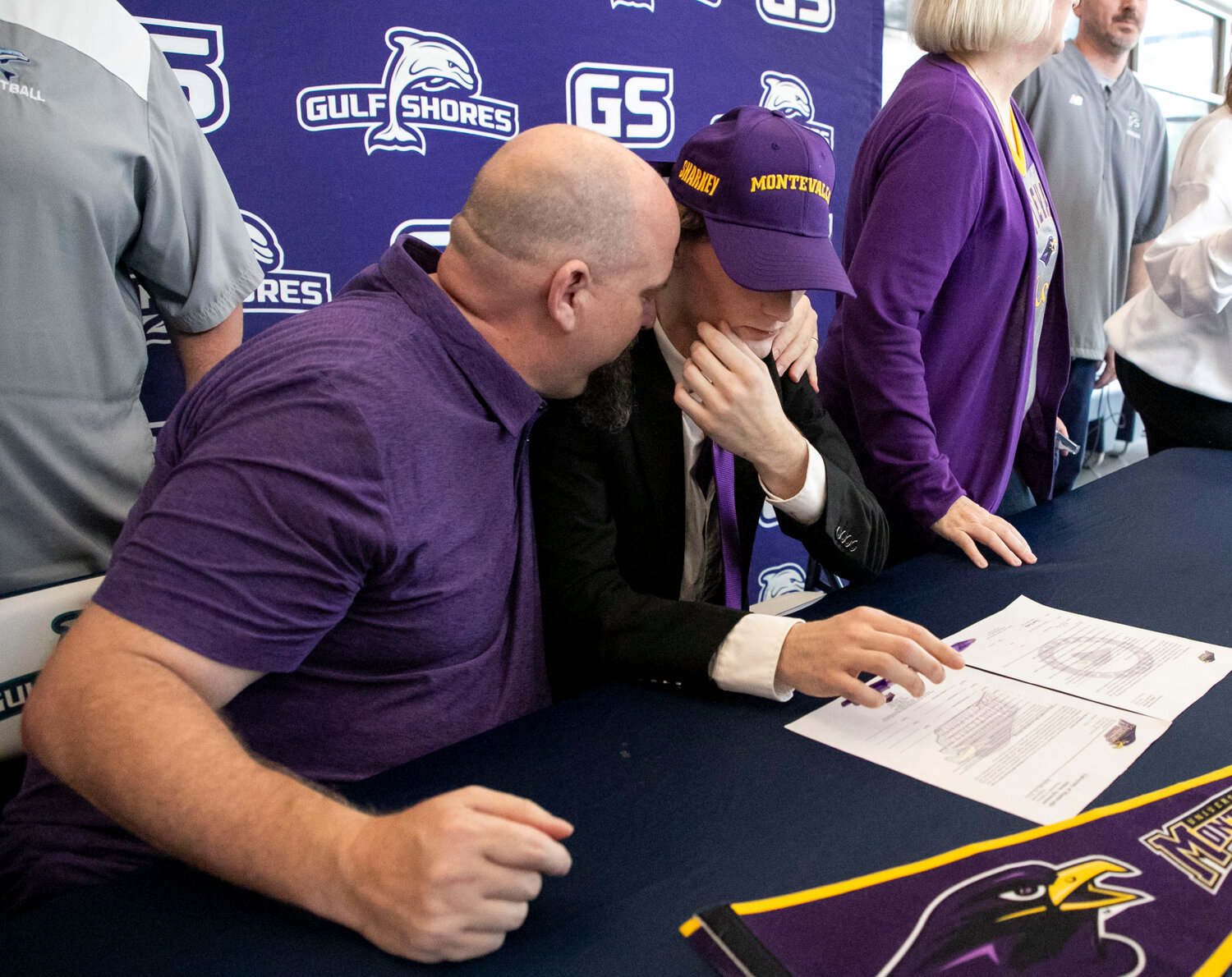 Chad Sharkey shares an embrace with his son Ethan after he cemented his commitment to be a two-sport athlete for the Montevallo Falcons on Wednesday, Jan. 24, following his time with the Gulf Shores Dolphins. Ethan is set to wrestle in the winter and run outdoor track in the spring.