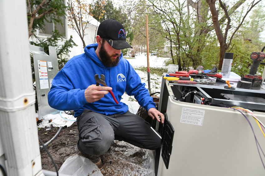 Chris Buckner, electrician, Foundation Systems Michigan, installs a Cummins whole house generator in Ypsilanti on Dec. 1, 2021, as increasing demand for generators and as people work from home and following this summer's storms. (Max Ortiz/The Detroit News/TNS)