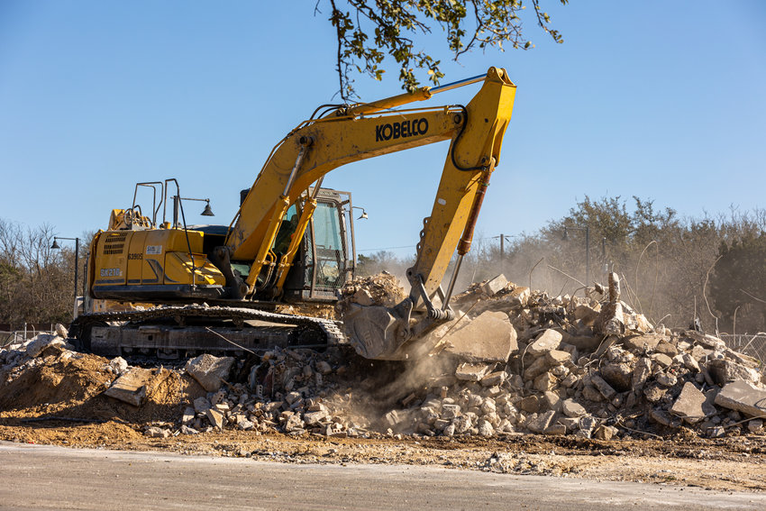 Cedar Park, TX, March 18, 2022: Workers use an excavator to clear demolition debris from the site of a former retail and office center along Bell Boulevard in Cedar Park to make way for the Bell District Redevelopment Project.