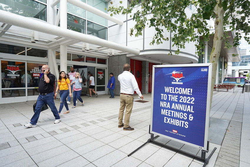 People walk past the entrance of the National Rifle Association Annual Meeting at the George R. Brown Convention Center, on May 27, 2022, in Houston. (Cecile Clocheret/AFP via Getty Images/TNS)