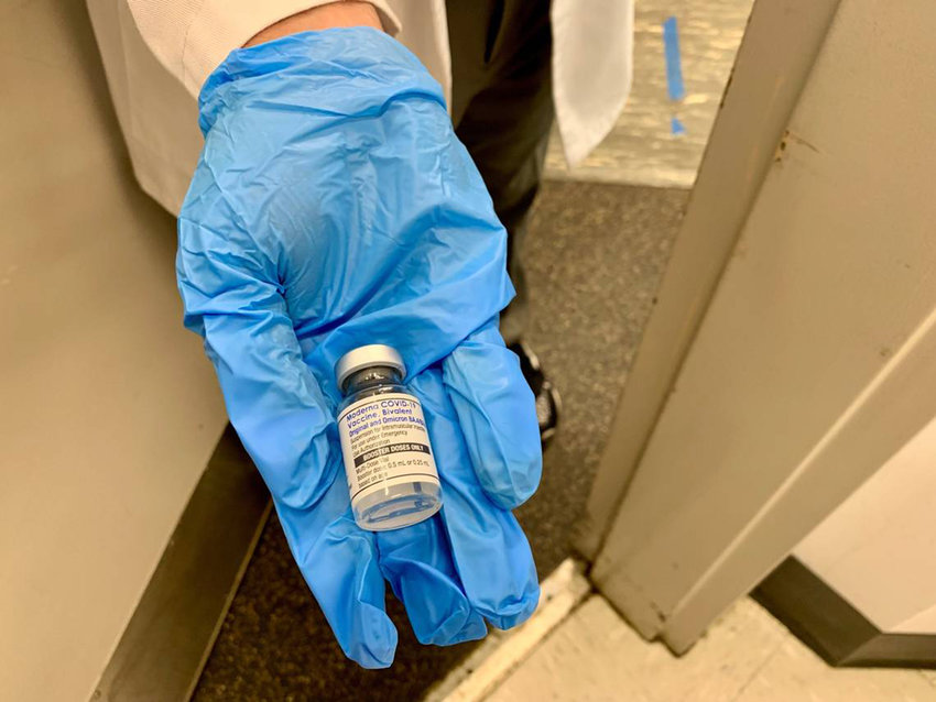 A nurse at a Walgreens pharmacy shows a patient the newly formulated Moderna bivalent vaccine on Sept. 7, 2022. The vaccine is an &quot;updated booster&quot; designed to target not only the original COVID-19 strain, but also omicron BA.4 and BA.5, which had surged in the U.S. in 2022.