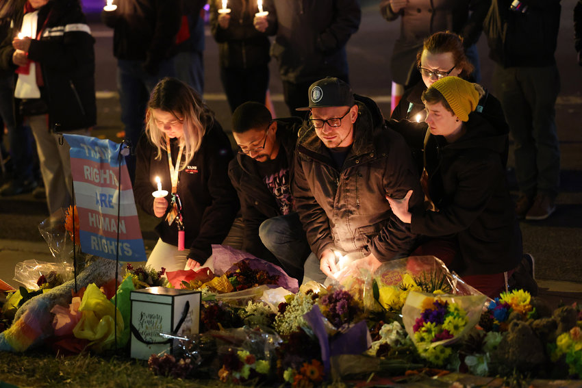 People hold a vigil at a makeshift memorial near the Club Q nightclub on Nov. 20, 2022, in Colorado Springs, Colorado, after a 22-year-old gunman entered the LGBTQ nightclub on Saturday, and opened fire, killing at least five people and injuring 25 others before being stopped by club patrons.