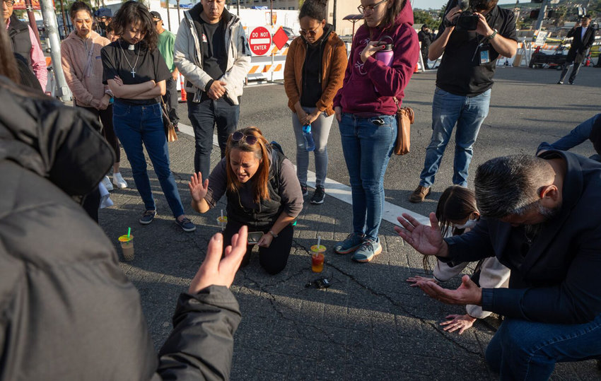 A prayer circle forms at the corner of Garvey Avenue and Garfield Avenue on Sunday, Jan. 22, 2023, near Star Dance Studio where 10 people were killed and 10 injured in a mass shooting Saturday night.