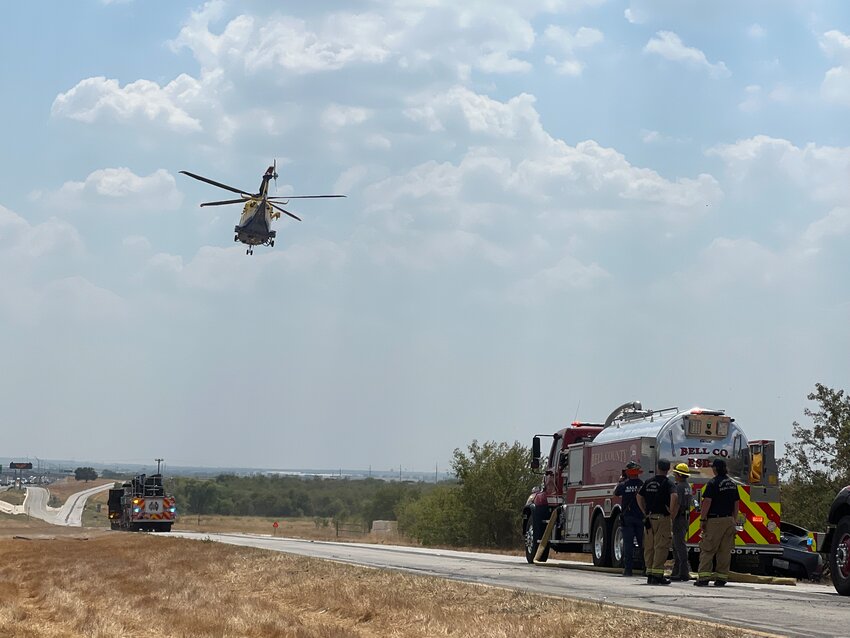 A helicopter flies over the IH-35 service road to survey a grass fire along the interstate near Jarrell on Friday, September 1.