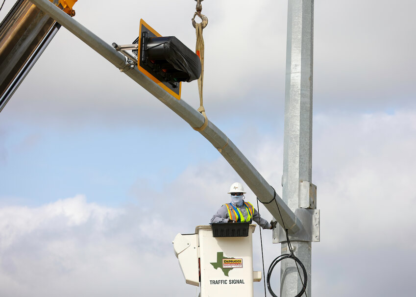 May 11, 2022, Leander, Texas: Construction workers hoist and fasten a traffic signal crossbar into place at the intersection of Main Street and San Gabriel Parkway, at the north entrance to the Northline mixed-use development project, often referred to as the city&rsquo;s &ldquo;new downtown district.&rdquo;