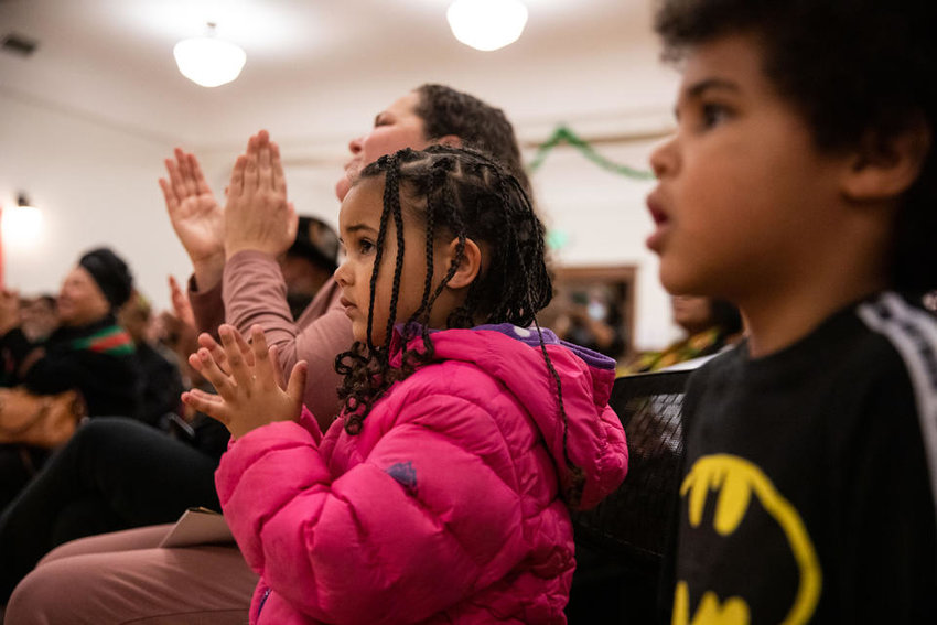 The audience claps after drummers and dancers from ADEFUA Cultural Education Workshop finish performing at Northwest African American Museum’s Kwanzaa celebration at Washington Hall on Thursday, Dec. 29, 2022. (Amanda Snyder/Crosscut)