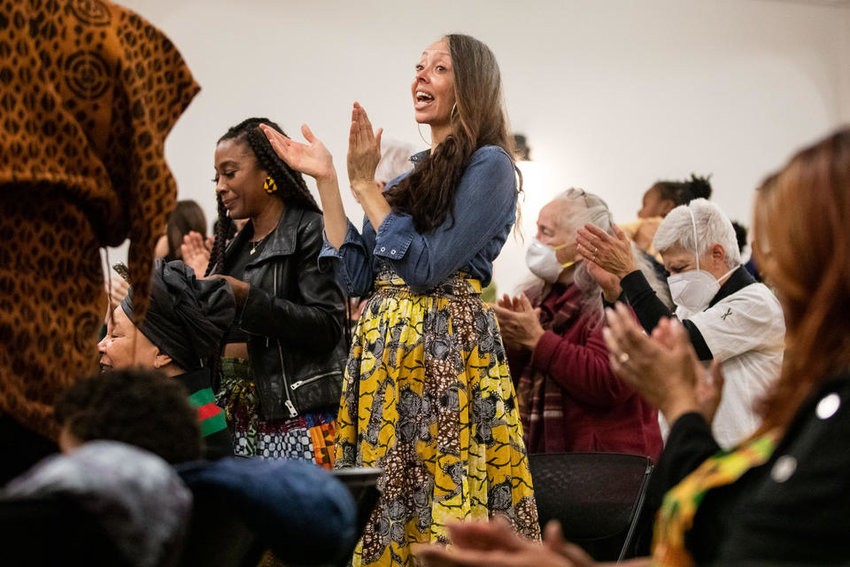 The audience claps as spoken word artist Tia Naché finishes her performance at Northwest African American Museum’s Kwanzaa event at Washington Hall on Thursday, Dec. 29, 2022. (Amanda Snyder/Crosscut)