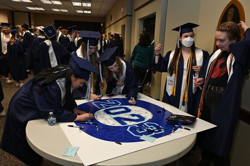 OHS 2023 graduates sign their school logo.