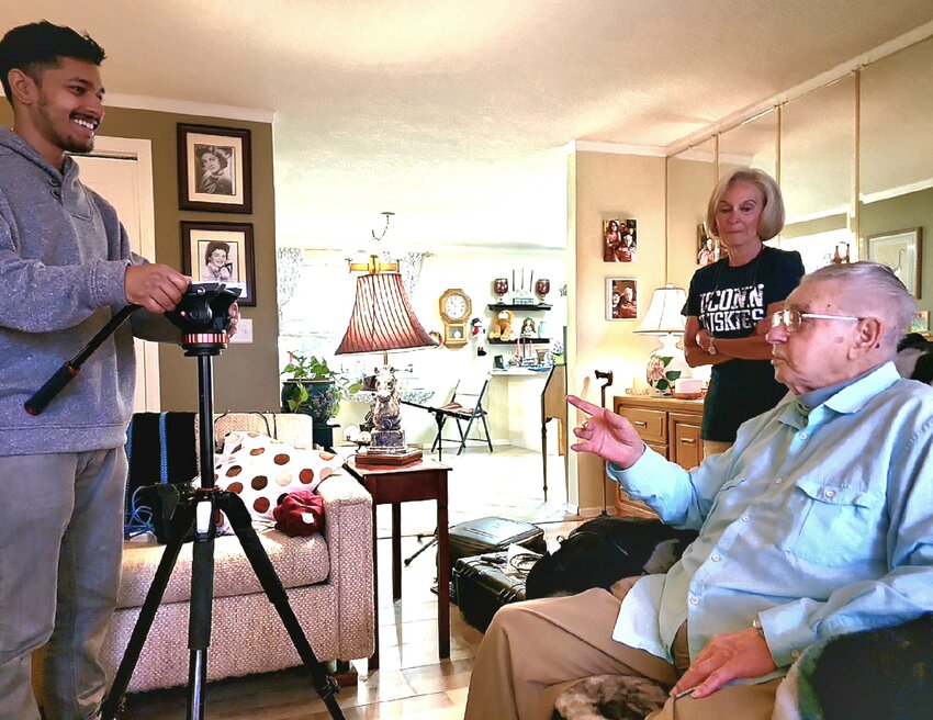 Rishi Sharma sets up his camera for an interview with Harvey Drahos, seated. Karen Schoessel stands behind. July 2, 2023.
