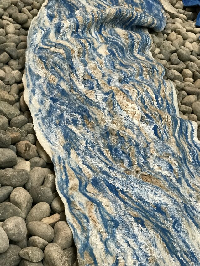 A very river looking felted fabric laid over river rocks for display